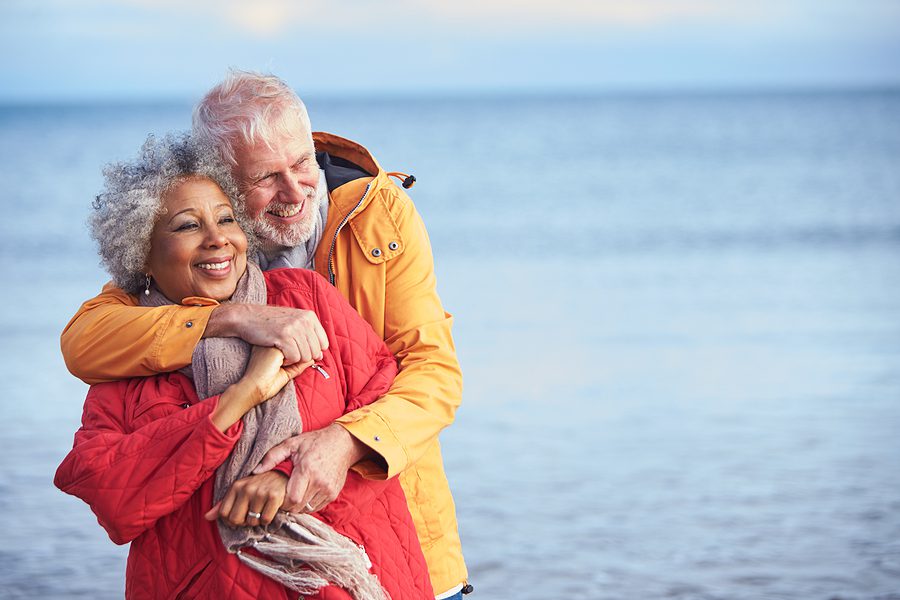 Walking along the beach is one of many winter activities for seniors Senior couple hugging along the shoreline during winter